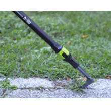 Škrabka na škáry for_q fitconnect odstraňuje burinu zo škáry v dlažbe vedľa trávnika.