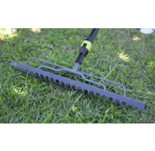 Kovové záhradné hrable na zelenom trávniku.