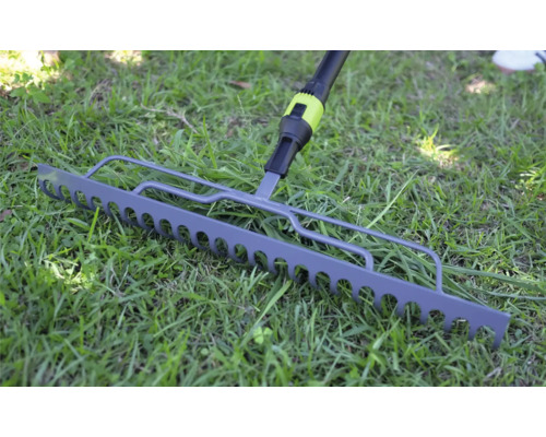 Kovové záhradné hrable na zelenom trávniku.