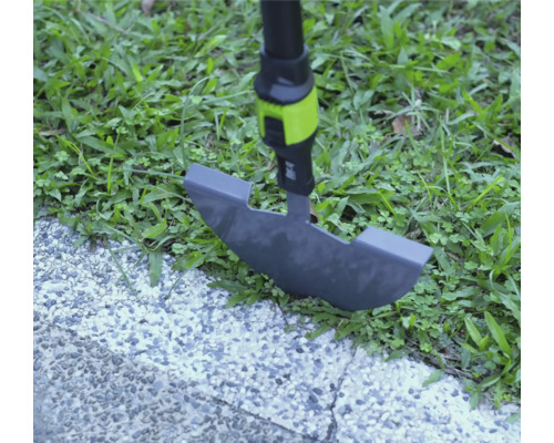 Zarovnávač trávnika pri práci na okraji trávnika medzi trávou a dláždeným chodníkom.