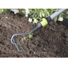 Záhradná motyčka z kovu pri práci v pôde vedľa rastliny.