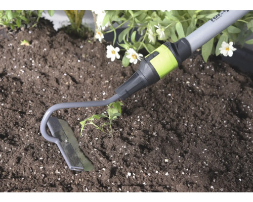 Záhradná motyčka z kovu pri práci v pôde vedľa rastliny.
