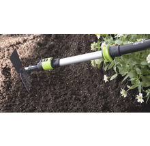 Kombinované záhradné náradie for_q s teleskopickou násadou v pôde vedľa kvetov.