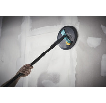 Ručná brúska Wolfcraft s teleskopickou násadou pri brúsení vytmelenej sadrokartónovej steny.