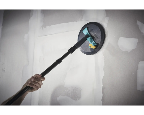 Ručná brúska Wolfcraft s teleskopickou násadou pri brúsení vytmelenej sadrokartónovej steny.