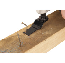 Multifunkčné náradie s pílovým listom reže klinec v drevenom tráme.