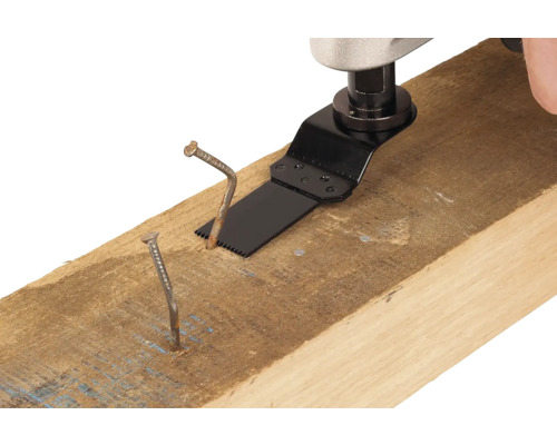 Multifunkčné náradie s pílovým listom reže klinec v drevenom tráme.