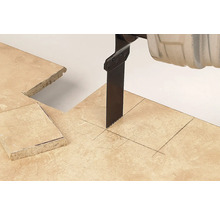 Pílový list chvostovej píly reže do kamennej dlaždice s vyznačenými čiarami a štvorcovým výrezom.