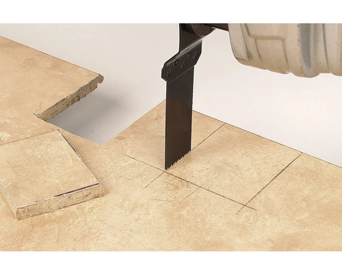 Pílový list chvostovej píly reže do kamennej dlaždice s vyznačenými čiarami a štvorcovým výrezom.