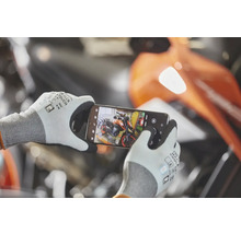 Osoba má na sebe pracovné rukavice s dotykovou funkciou a smartfónom fotografuje motocykel v dielni.