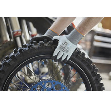 Pracovné rukavice Gebol Master Flex Cool a Touch držiace pneumatiku motocykla s terénnym profilom v dielni.