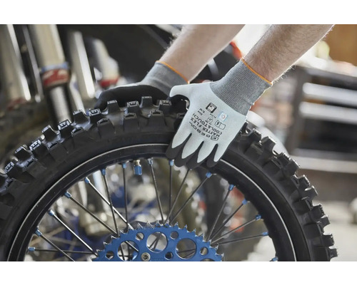 Pracovné rukavice Gebol Master Flex Cool a Touch držiace pneumatiku motocykla s terénnym profilom v dielni.