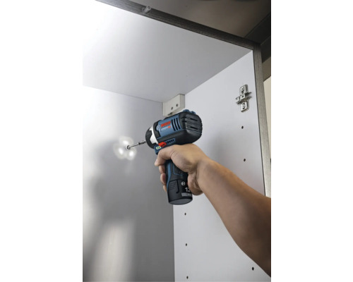 Akumulátorový rázový uťahovák Bosch pri skrutkovaní skrutky do bielej skrine.