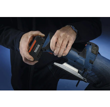 Osoba vkladá akumulátor zo systému Bosch Professional 18 voltov do priamočiarej píly.