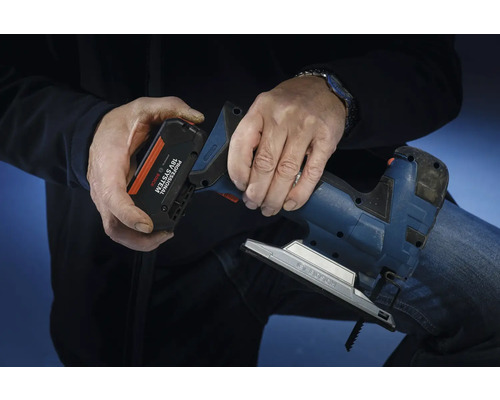 Osoba vkladá akumulátor zo systému Bosch Professional 18 voltov do priamočiarej píly.