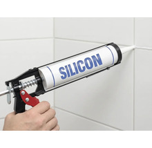 Nanášanie silikónu pomocou vytlačovacej pištole na škáru obkladu.