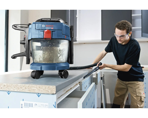 Akumulátorový vysávač na mokré a suché vysávanie Bosch pri čistení pracovného stola v svetlej dielni.