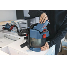 Osoba vkladá 18-voltový akumulátor do akumulátorového vysávača Bosch Professional GAS 18 Volt-1 v dielni.