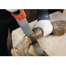 Osoba reže drevené poleno ručnou pílou na pracovnom stole.