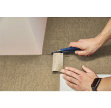 Osoba reže štruktúrovanú plstenú podlahovú krytinu odlamovacím nožom.