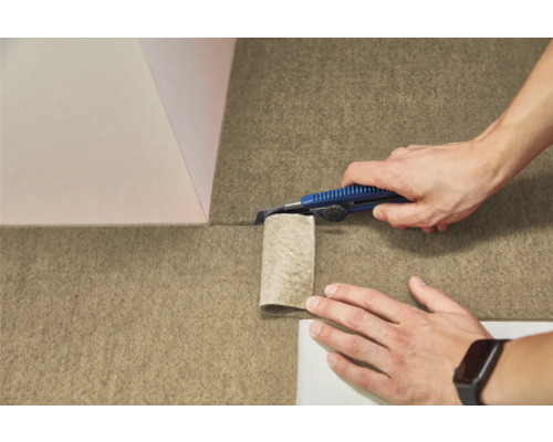 Osoba reže štruktúrovanú plstenú podlahovú krytinu odlamovacím nožom.