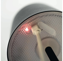 Detail svietidla so zapojeným nabíjacím káblom USB a svietiacim indikátorom nabíjania.