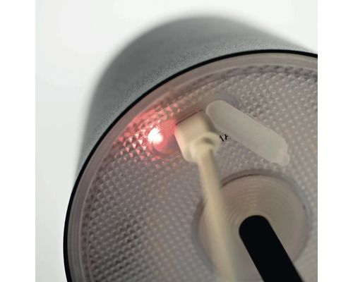 Detail svietidla so zapojeným nabíjacím káblom USB a svietiacim indikátorom nabíjania.