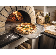Čerstvo upečená pizza na lopate na pizzu s Tenneker Logo pred horiacou kamennou pecou v rustikálnej kuchyni.