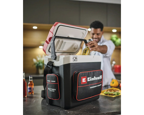 Akumulátorový chladiaci box Einhell Power X-Change v kuchyni, muž vyberá fľašu s nápojom z otvoreného boxu s vreckami na príslušenstvo.