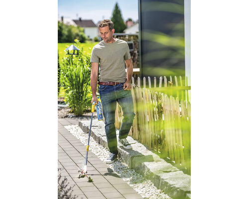 Muž používa plynový vypaľovač buriny na dláždenej záhradnej ploche na odstraňovanie buriny medzi dlaždicami.