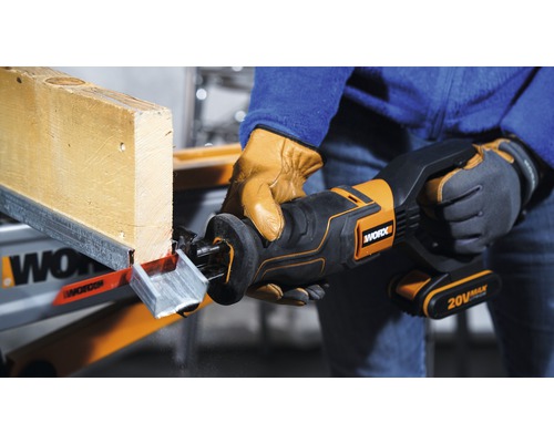 Osoba reže drevenú dosku akumulátorovou šabľovou pílou. Píla je od spoločnosti Worx.