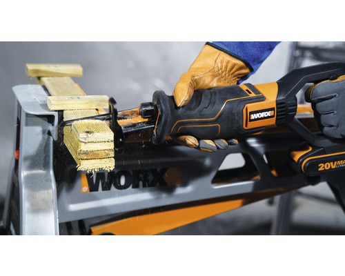 Akumulátorová chvostová píla reže drevo na pracovnom stole, ovláda ju osoba v rukaviciach, viditeľné logo Worx.