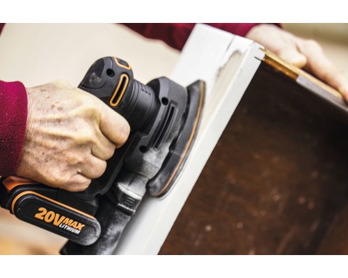 Osoba používa excentrickú brúsku na brúsenie kusu dreva.