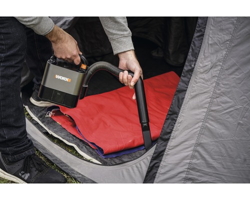 Osoba používa akumulátorový vysávač WORX v stane.