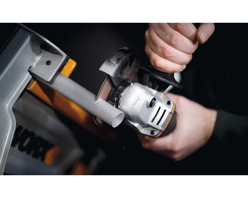 Osoba reže rúru uhlovou brúskou v dielni. Logo Worx.