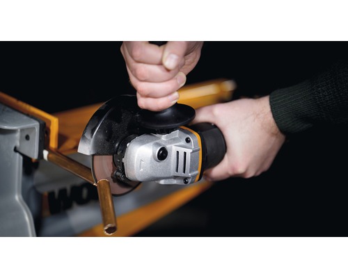 Detailný záber osoby rezu kovovej rúrky uhlovou brúskou.