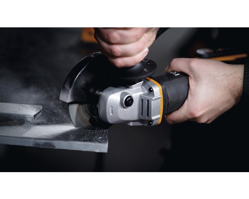 Ruka drží uhlovú brúsku pri brúsení kusu kovu.