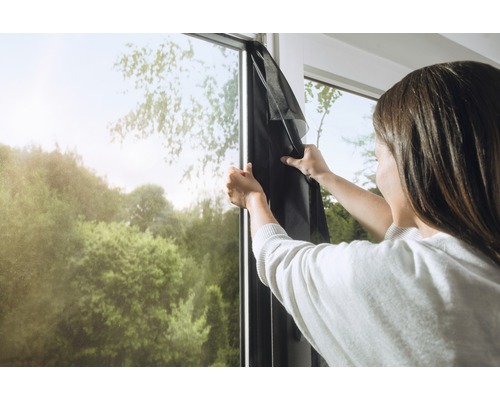 Žena upevňuje sieť proti hmyzu na okenný rám