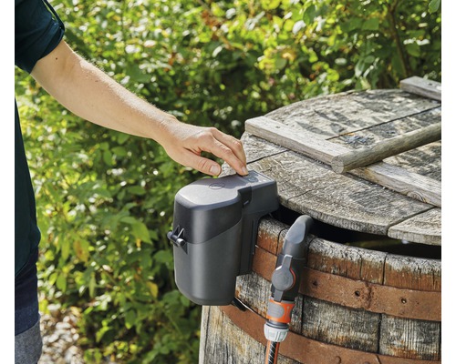 Automatické zavlažovanie záhrady so zavlažovacím čerpadlom namontovaným na drevenom sude.