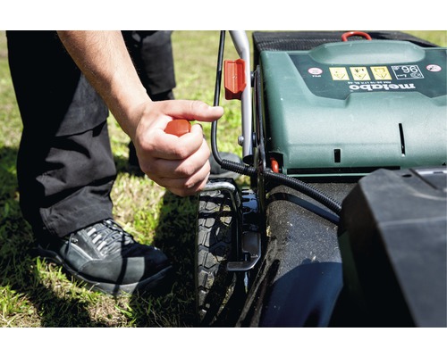 Osoba štartuje kosačku na trávu značky Metabo