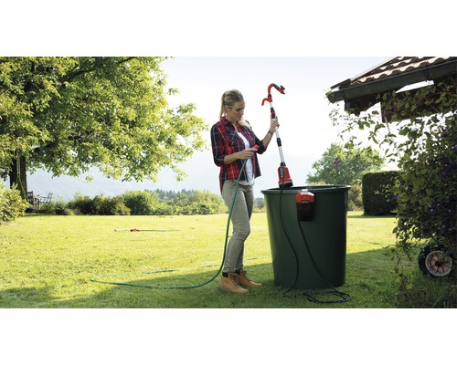 Žena obsluhuje teleskopický záhradný zavlažovač na zavlažovanie rastlín v záhrade.