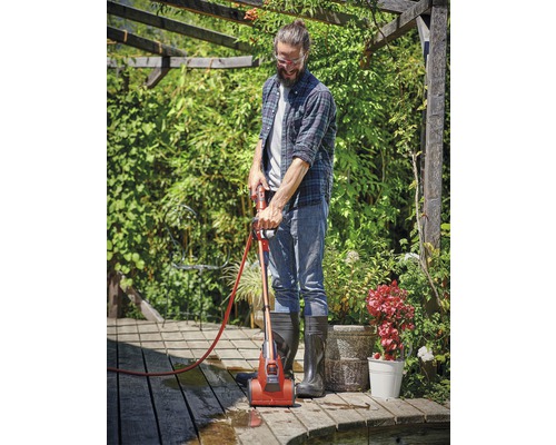 Muž čistí drevenú terasu čističom terás v záhrade