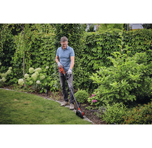 Muž strihá okraje trávnika zastrihávačom trávnika v záhrade.