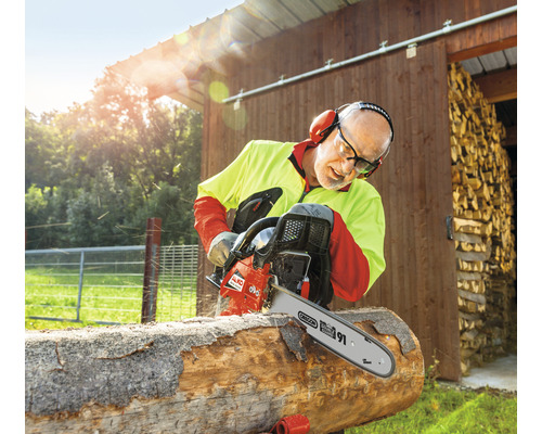 Muž pília drevo s motorovou pílou AL-KO vonku.