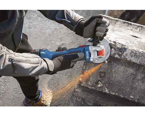 Osoba používa akumulátorovú uhlovú brúsku na rezanie betónu.