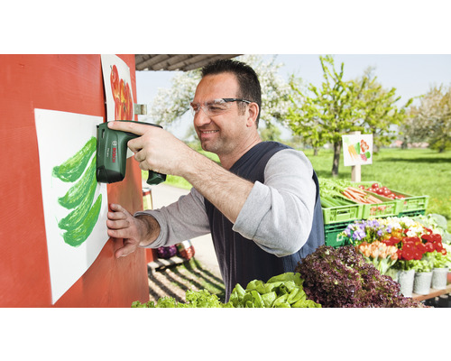 "Muž pripevňuje elektrickou zošívačkou list papiera na drevenú konštrukciu