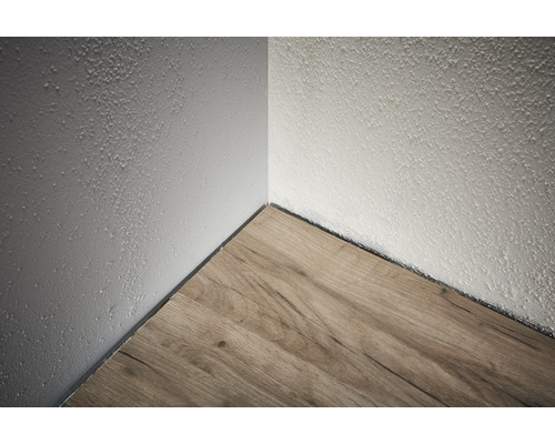 Roh miestnosti s laminátovou podlahou a stenou s hrubou omietkou