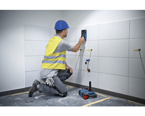 Remeselník používa detektor na obkladanej stene v kúpeľni.