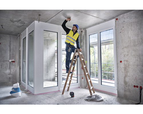 Interiérová scéna v hrubej stavbe s remeselníkom na rebríku pracujúcim na strope.