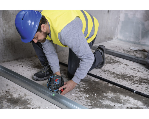 Remeselník používa laserovú vodováhu na vyrovnanie kovovej lišty